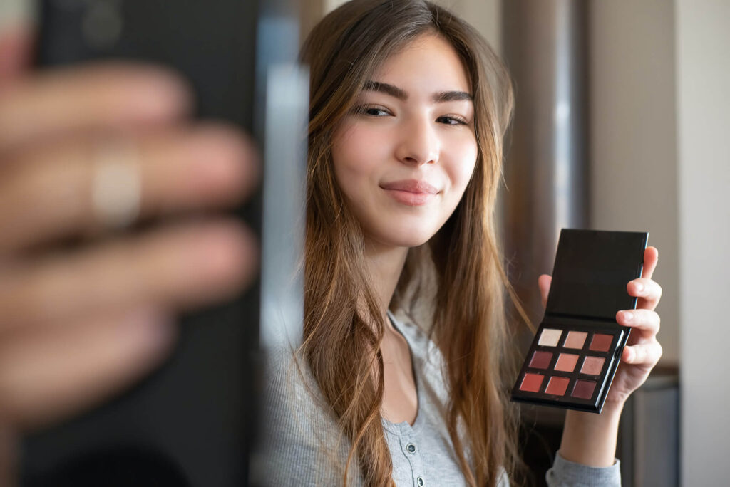 Young women holding up makeup palette 